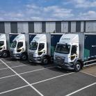 A fleet of five Tremco trucks parked in a row in front of a warehouse.