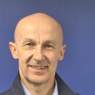 Headshot of a man in front of a purple background