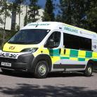 A ambulance parked in a car park, surrounding by tress