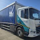 A Wilson James branded DAF XD Electric rigid, parked in a depot on a sunny day