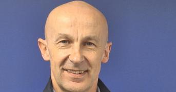 Headshot of a man in front of a purple background