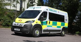 A ambulance parked in a car park, surrounding by tress