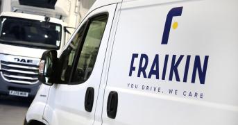 The image shows a white Fraikin van in the foreground with the company logo and slogan "You Drive, We Care" on its side. In the background, there is a DAF truck inside a garage or warehouse setting.