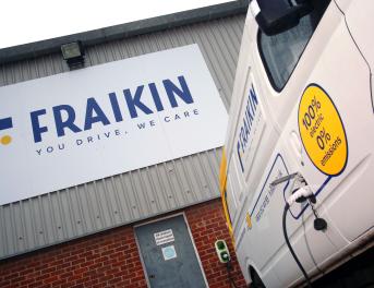 A Fraikin electric vehicle is parked at a charging station beside a building. The building features a large Fraikin sign with the tagline "You drive. We care." The vehicle displays text about being 100% electric with zero emissions.