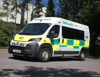 A ambulance parked in a car park, surrounding by tress