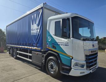 A Wilson James branded DAF XD Electric rigid, parked in a depot on a sunny day