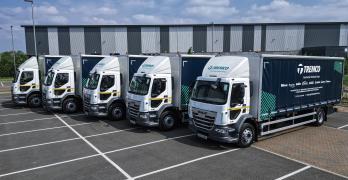 A fleet of five Tremco trucks parked in a row in front of a warehouse.