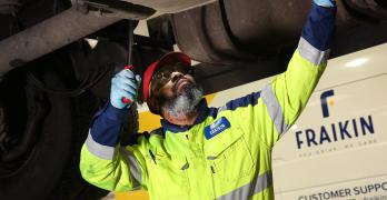 Fraikin mechanic checks under a vehicle raised on a ramp
