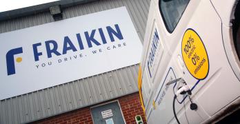 A Fraikin electric vehicle is parked at a charging station beside a building. The building features a large Fraikin sign with the tagline "You drive. We care." The vehicle displays text about being 100% electric with zero emissions.