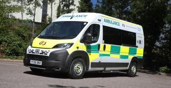 A ambulance parked in a car park, surrounding by tress